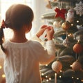 back view little girl putting decor toy on the Christmas tree