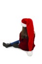 Back view of little girl in red Santa hat sitting on the floor looking down. Rear view. Royalty Free Stock Photo