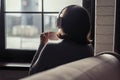 Back view of lonely ÃÂaucasian young woman enjoying having breakfast with cup of coffee and listenning music in headphones