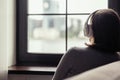 Back view of lonely brunette woman in headphones listen music sitting near window . Concept. Royalty Free Stock Photo