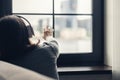 Back view of lonely brunette woman in headphones listen music and touching window . Concept. Royalty Free Stock Photo