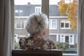 Back view of lonely elderly woman with gray hair looking out of window Royalty Free Stock Photo