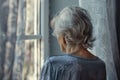 Lonely elderly woman with gray hair looking out of window Royalty Free Stock Photo