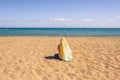 Back view of lonely Muslim woman  traveler in a colorful headscarf, scarf sitting on the sand on the beach and looking on the sea. Royalty Free Stock Photo