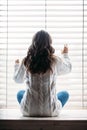 Back view of lonely woman sitting on window sill Royalty Free Stock Photo