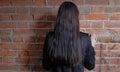 Back view of long haired brunette women against red brick wall Royalty Free Stock Photo