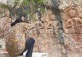 Back view of a long haired man taking photo of Gyalwa Ringna 5 Dhyani Buddha rock statue while sitting