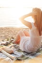 Back view of long haired young woman sitting alone on beach picnic Royalty Free Stock Photo