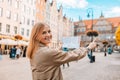 Back view of happy young woman tourist with trendy look with map visiting city and looking around, searching direction Royalty Free Stock Photo