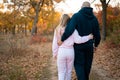 Back view of loving couple hugging walking along track in autumn countryside or park Royalty Free Stock Photo