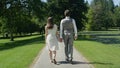 BACK VIEW: Loving couple strolling through the lovely green park hand in hand Royalty Free Stock Photo
