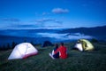 Back view, loving people sitting near camping enjoying sunrise in mountains Royalty Free Stock Photo