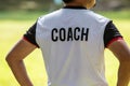 Back view of male soccer or football coach in white shirt with w