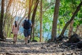 Back view of male tourist and his daughter walking together in forest nature path walk on trail woods background at Hellfire Pass