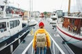 Back view of male tourist with traveling backpack wearing yellow raincoat standing on pier Royalty Free Stock Photo