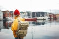 Back view of male tourist with traveling backpack wearing yellow raincoat standing on pier Royalty Free Stock Photo