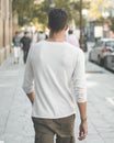 Back view of a male with a white long sleeve t-shirt walking on the sidewalk