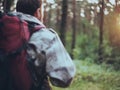 Back view of man with backpack in camouflage unionalls walking through the forest alone. Hunter exploring the territory.