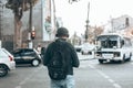 Back view of man in casual clothes with a backpack listening to music in headphones on the street outdoors Royalty Free Stock Photo