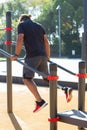 Back view of man with disability training on bars