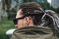Back view of man with dreadlocks listening music with headphones or earphones outdoor. Close up Royalty Free Stock Photo