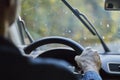 Back view of a man driving a car with moving windshield wipers during rain