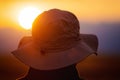 Back view of a man with explorer hat watching scenic sunset. Concept for travel exploration and discovery.