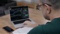 Back view of man analysing stock market charts on laptop. Bitcoin and crypto currency investment