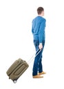 Back view of man with green suitcase looking up.