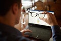 Back view of man hand holding eyeglasses in front of laptop screen with charts and diagrams. Poor eyesight threatment Royalty Free Stock Photo