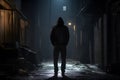 Back view of man in hood in dark empty street at night. Concept for crime, robbery and assault Royalty Free Stock Photo