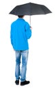 Back view of man in jeans under an umbrella. Royalty Free Stock Photo