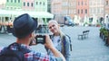 Back view of man making photos of woman tourist on the view of city market square