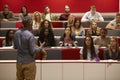 Back view of man presenting to students at a lecture theatre Royalty Free Stock Photo