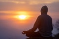 Back view of man is relaxingly practicing meditation yoga mudra at mountain top with sunrise in winter to attain happiness from Royalty Free Stock Photo