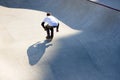 Back view of man on roller skates in motion at modern roller skate park. Roller skater doing dangerous and daring tricks