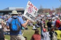 Back view of man in shorts and teeshirt with hat and backpack at gun control rally with a sign that says LOVE KIDS - Ban ARs not