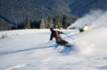 Man skiing on prepared slope with fresh snow. Snow gun machine making artificial snowfall. Magic nature on background.