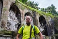 Back view of a man standing alone in front of ancient sacred royal tombs Gunung Kawi. Man is dressed traditional sarong