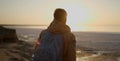 Back view man traveler with backpack meeting sunrise at deserted sea beach