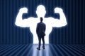 Back view of man with very strong illuminated shadow flexing muscles on dark wall background. Personal development, inner strength Royalty Free Stock Photo