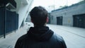 Back view of man walking on urban street. Man going on city street.