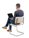 Back view of a man who sits on a chair with a laptop Royalty Free Stock Photo