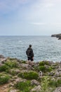 Back view of a mature man with backpack looking at the sea with his dog in nature. Royalty Free Stock Photo