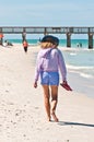 Adult female walking along a sandy, tropical shoreline