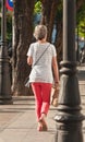 Woman walking a sidewalk with hand bag in Cadiz, Spain