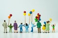 Back view of miniature happy family holding balloons with white