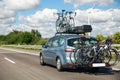 Back view modern white family wagon car with mounted roof box trunk and bike tail carrier driving european highway road Royalty Free Stock Photo