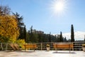 Back view of modern wooden empty lounger chair and bench on patio balcony terrace against bright yellow orange autumn