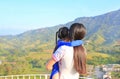 Back view of mom carrying daughter on balcony at hillside with looking at mountain
